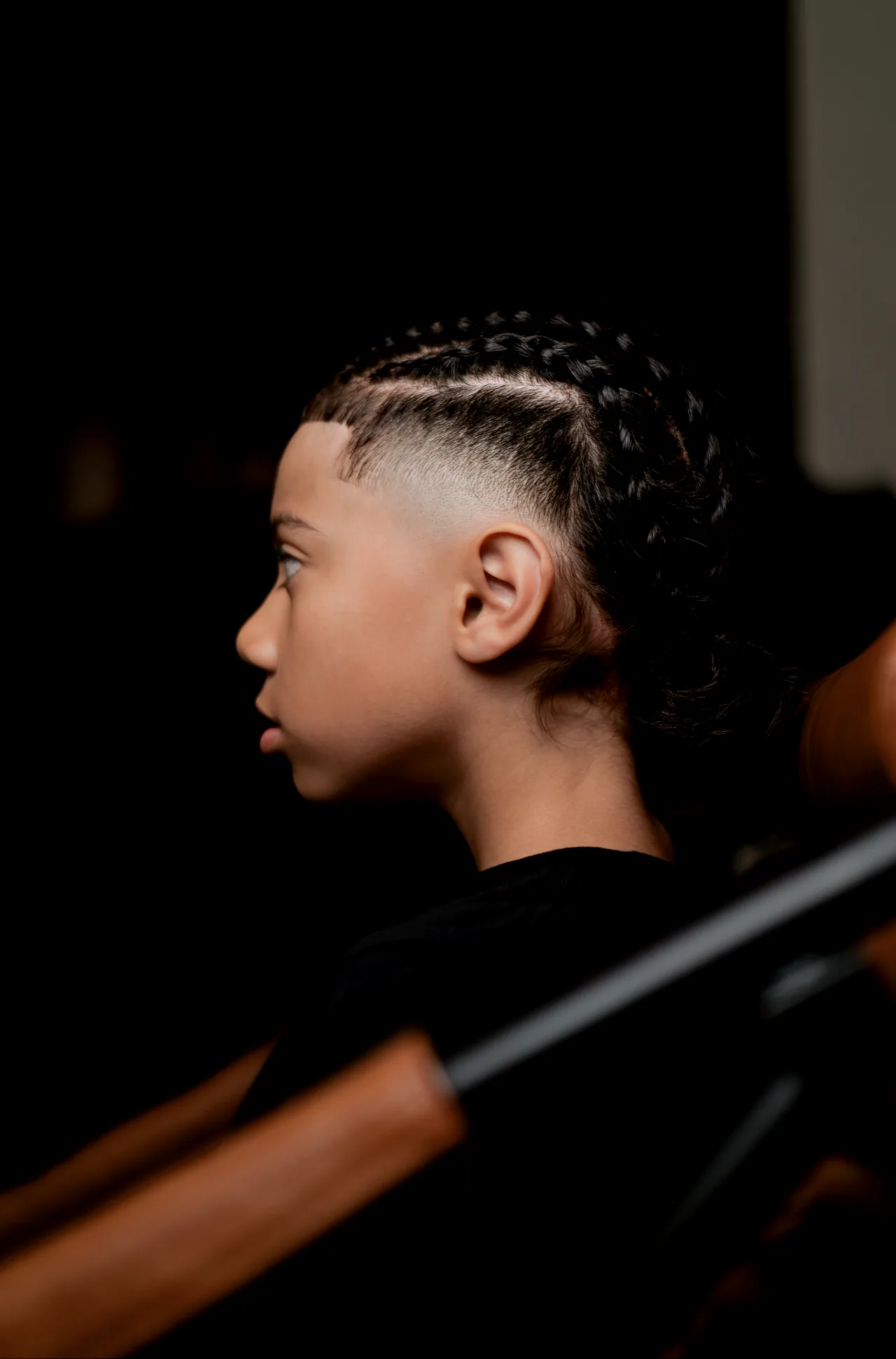 Young client in profile showing finished braids with a clean fade