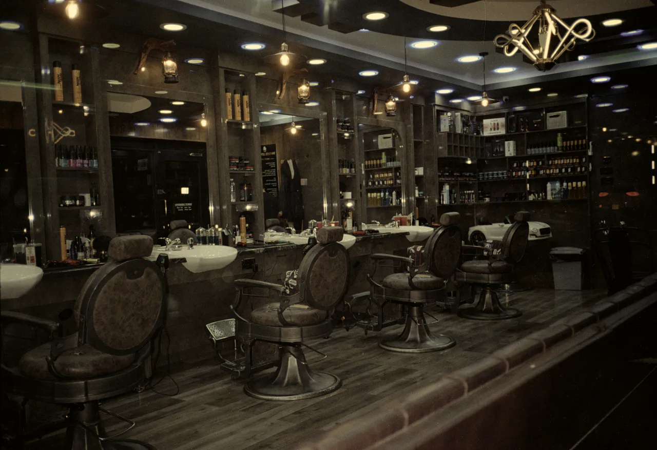 Wide view of a barbershop floor with leather chairs and warm lighting